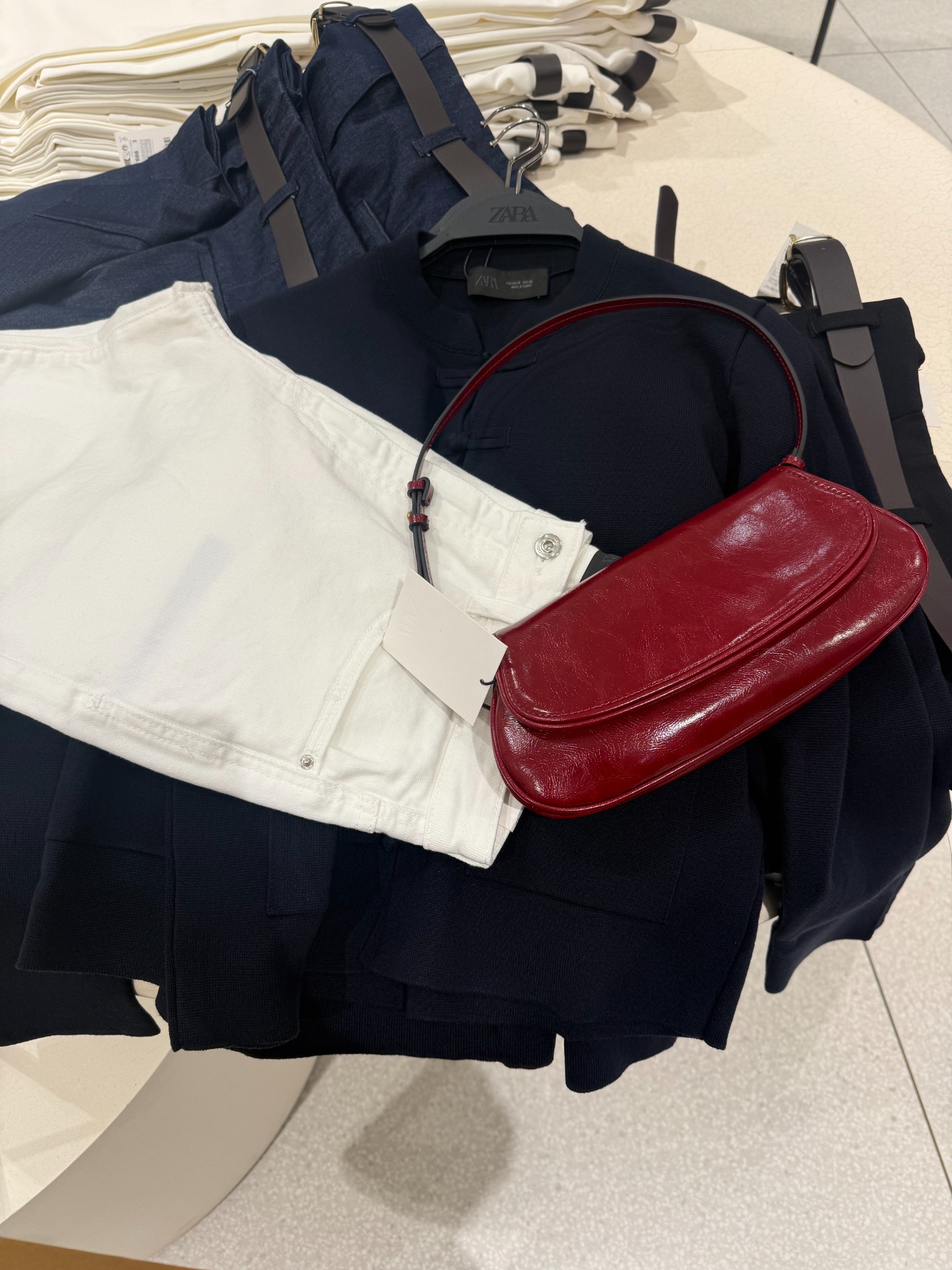 Selección en tienda de prendas azules y blancas con un bolso rojo